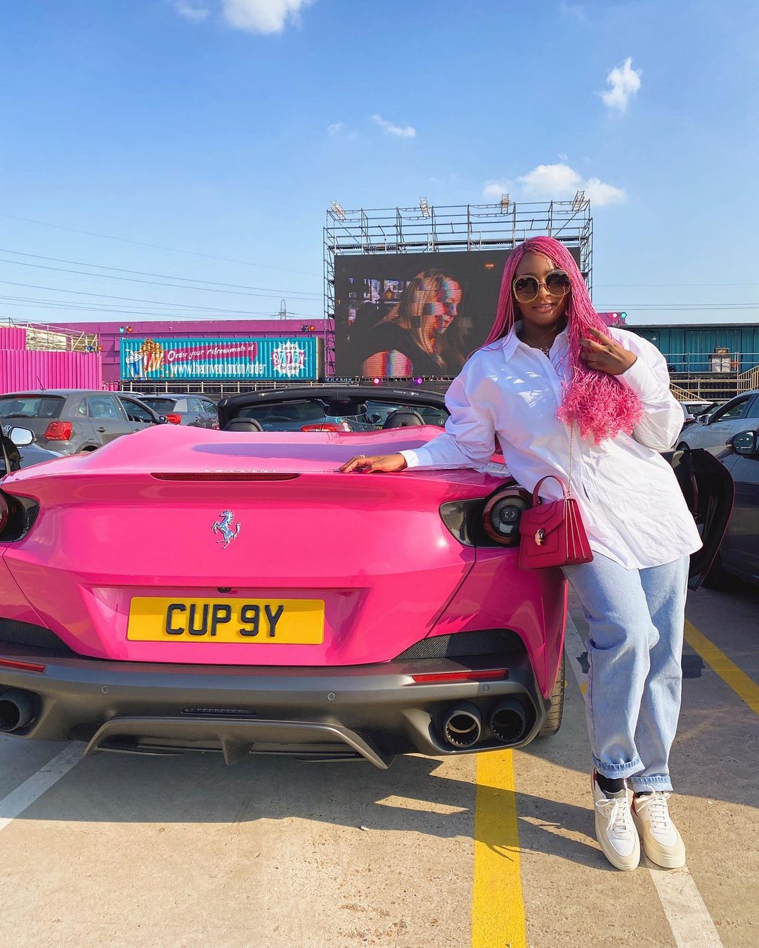Cuppy posing with one of her Ferrari cars. Source: Instagram @cuppymusic
