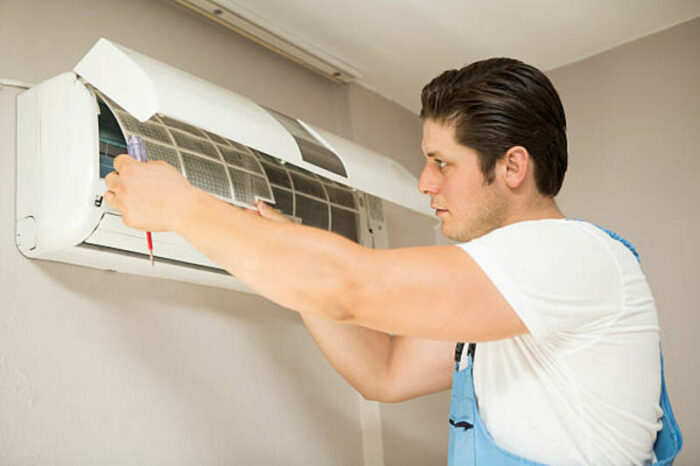 Young technician repairing air conditioner at home
