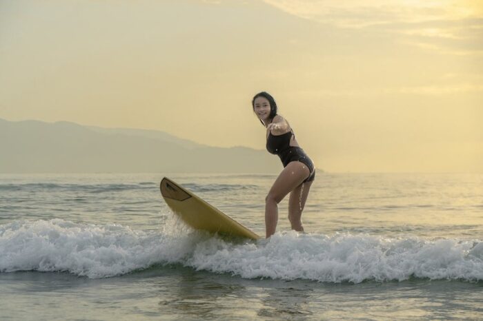 A Woman in Black Swimsuit Surfing
