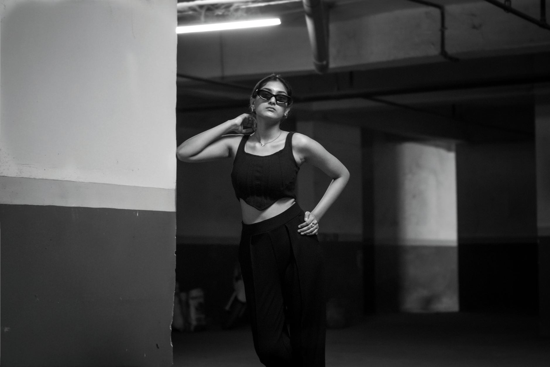 Black and white portrait of a stylish woman in a bold, confident pose.