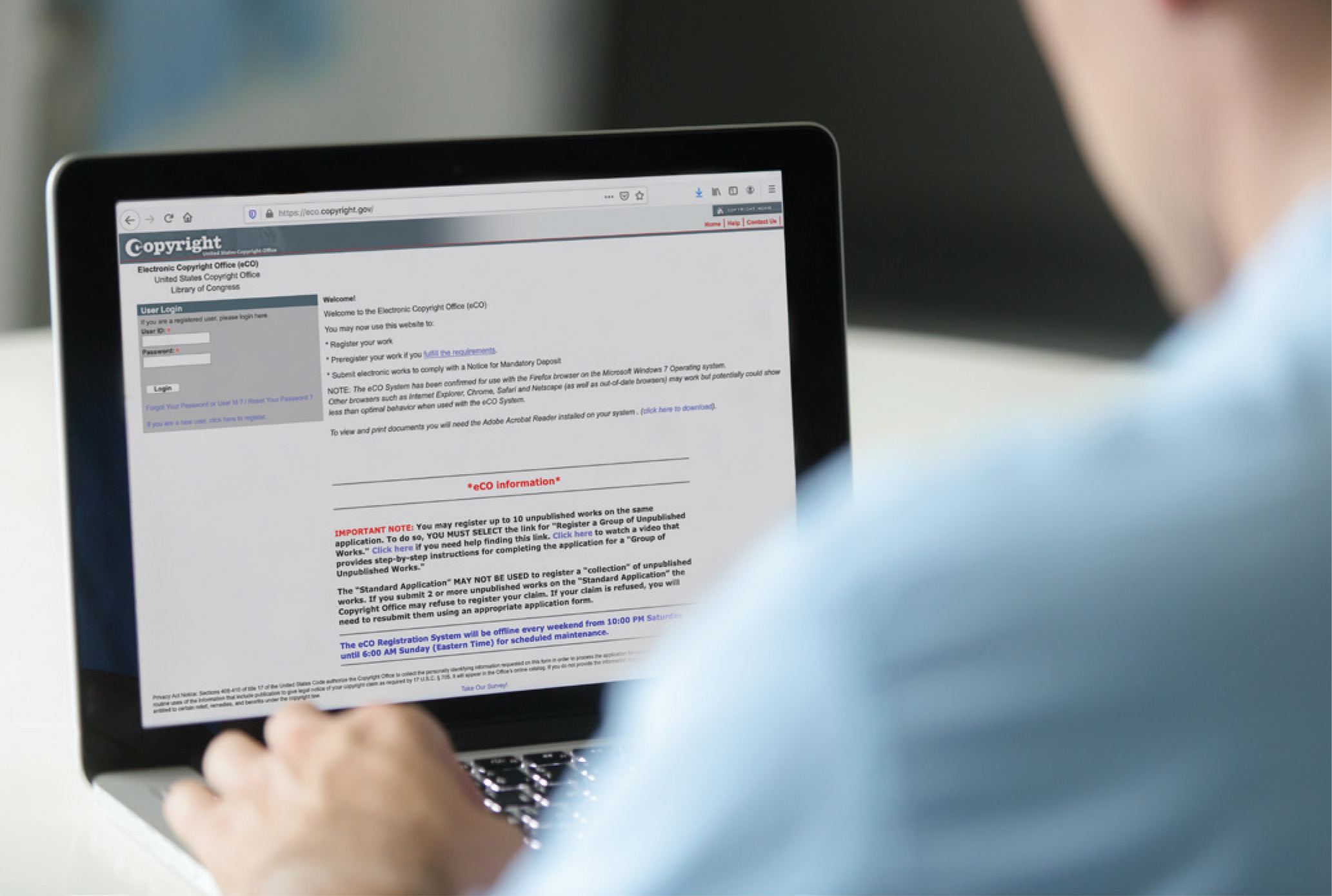 Copyright registration documents and certificates on desk with registration portal on laptop