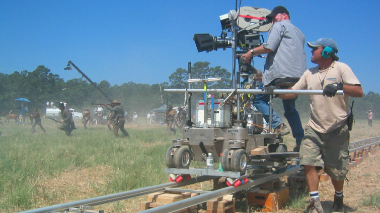 Cinematographer operating a professional camera on a dolly track in a studio