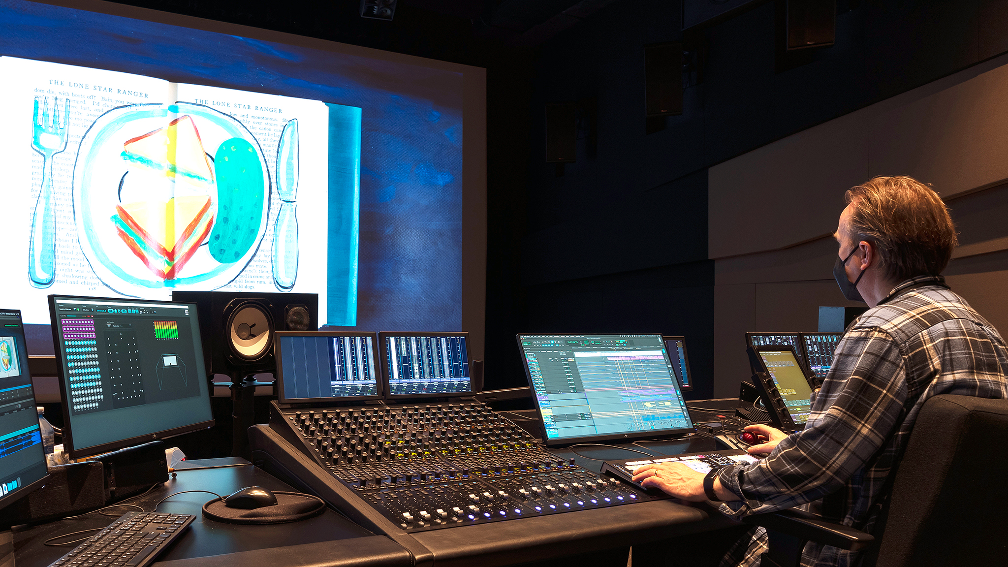 Professional film sound mixing studio with console, speakers, and film playing on screen