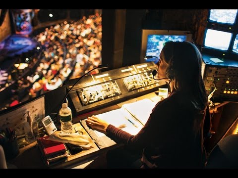 Backstage view of Broadway theater during performance with stage managers and crew
