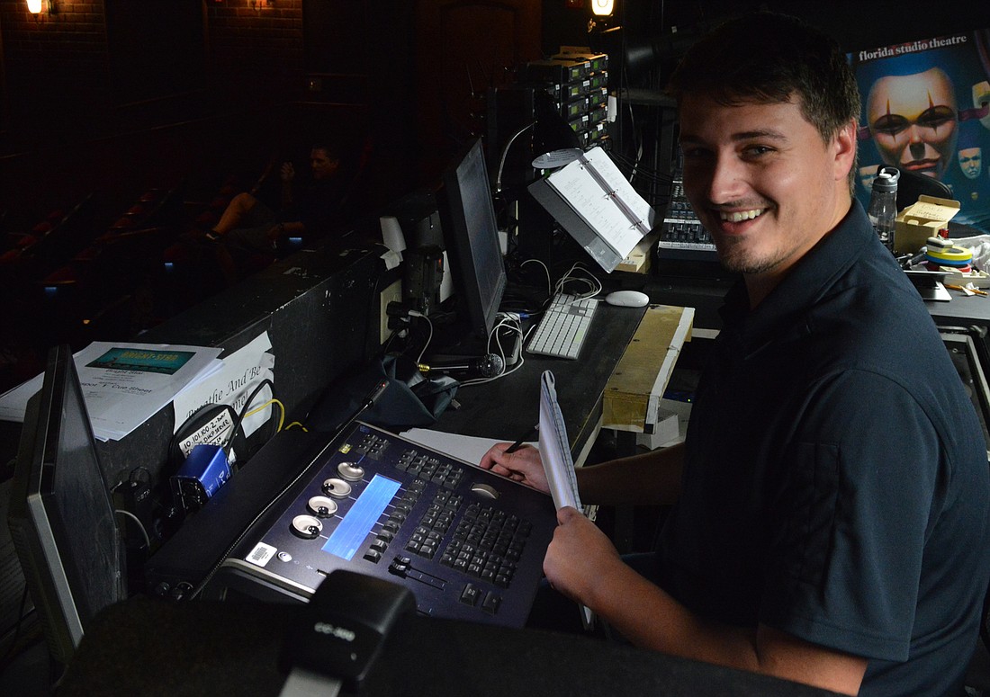 Lighting designer working at a lighting console backstage with the stage visible in the background