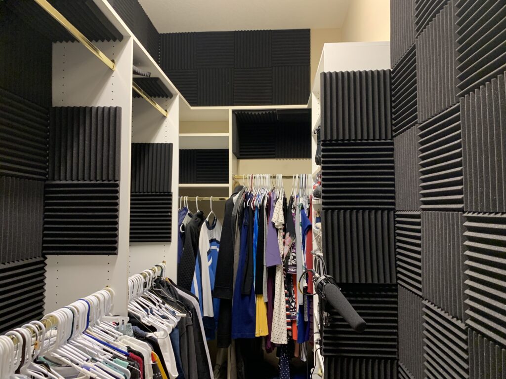 Home voice recording booth set up inside a walk-in closet with acoustic treatment and professional microphone