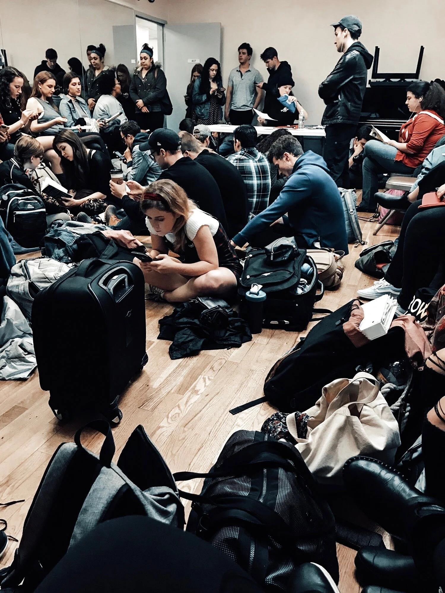 Actor sitting in a hallway outside a casting room holding script pages with other actors waiting in background