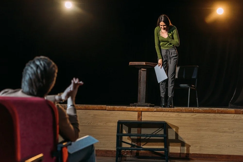Actor performing on a theater stage in front of casting directors during an open audition